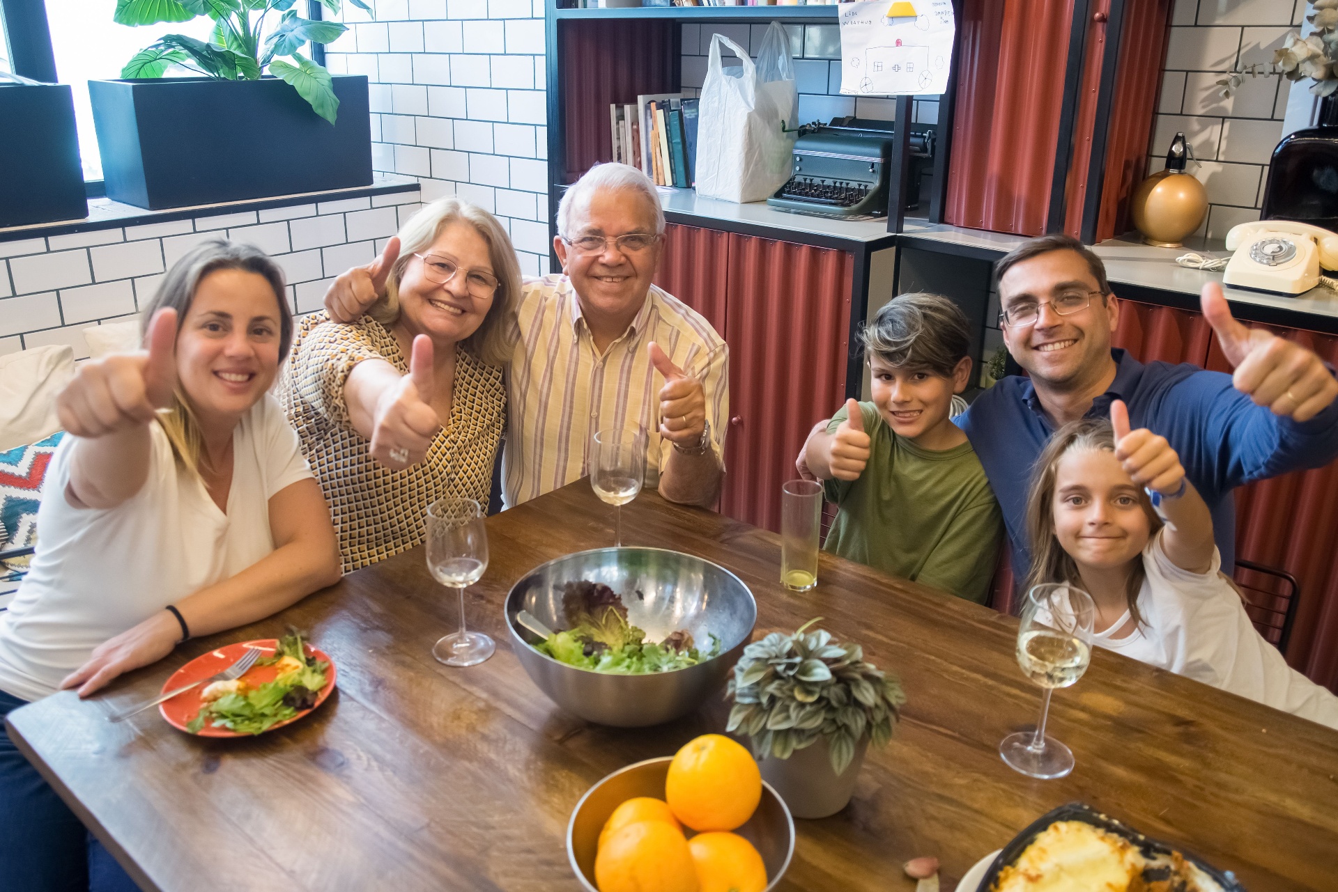 Familia disfrutando una comida juntos, dando el pulgar arriba